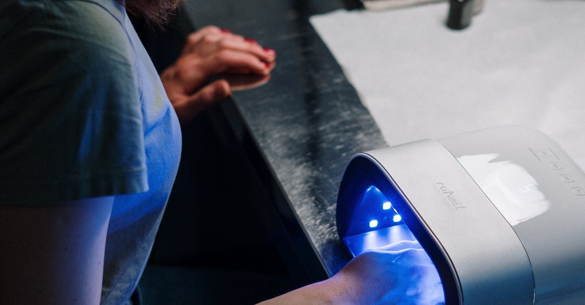 Woman receiving a gel manicure with UV lamp at a nail salon.